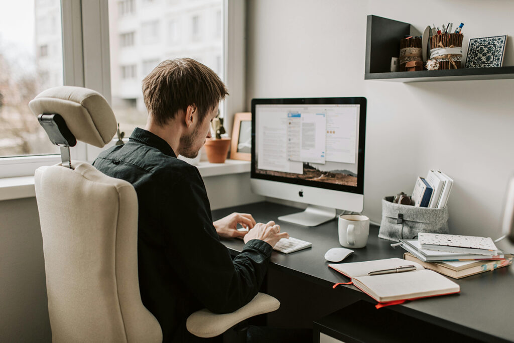 man working at a desk at home using a computer