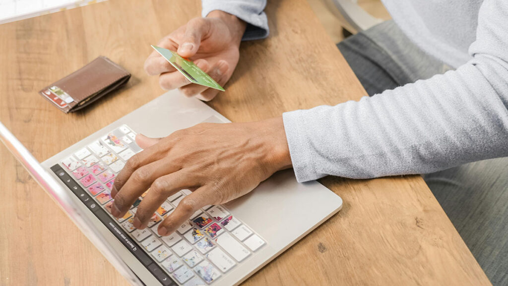 man typing a credit card into a laptop